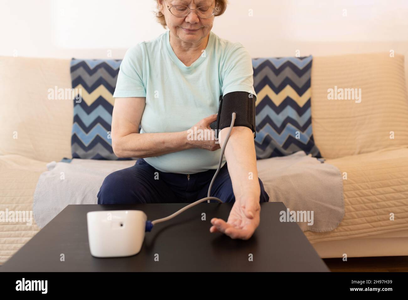 Senior woman taking measures blood pressure at home indoor. Self care