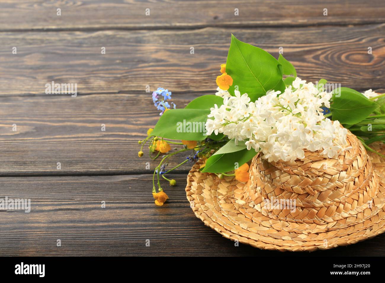 bouquet of spring flowers in a straw hat on a wooden background Stock ...
