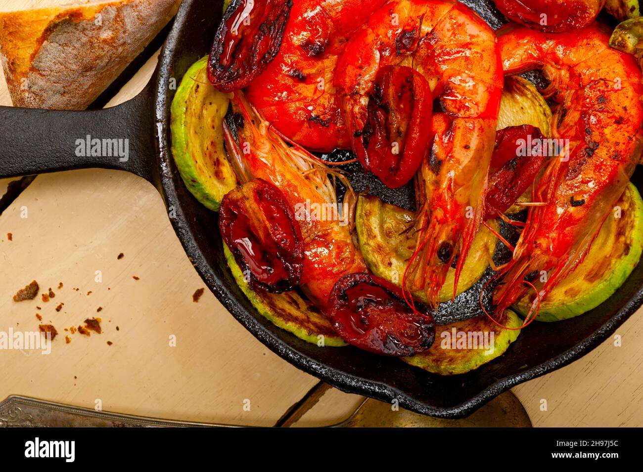roasted shrimps on cast iron skillet with zucchini and tomatoes Stock