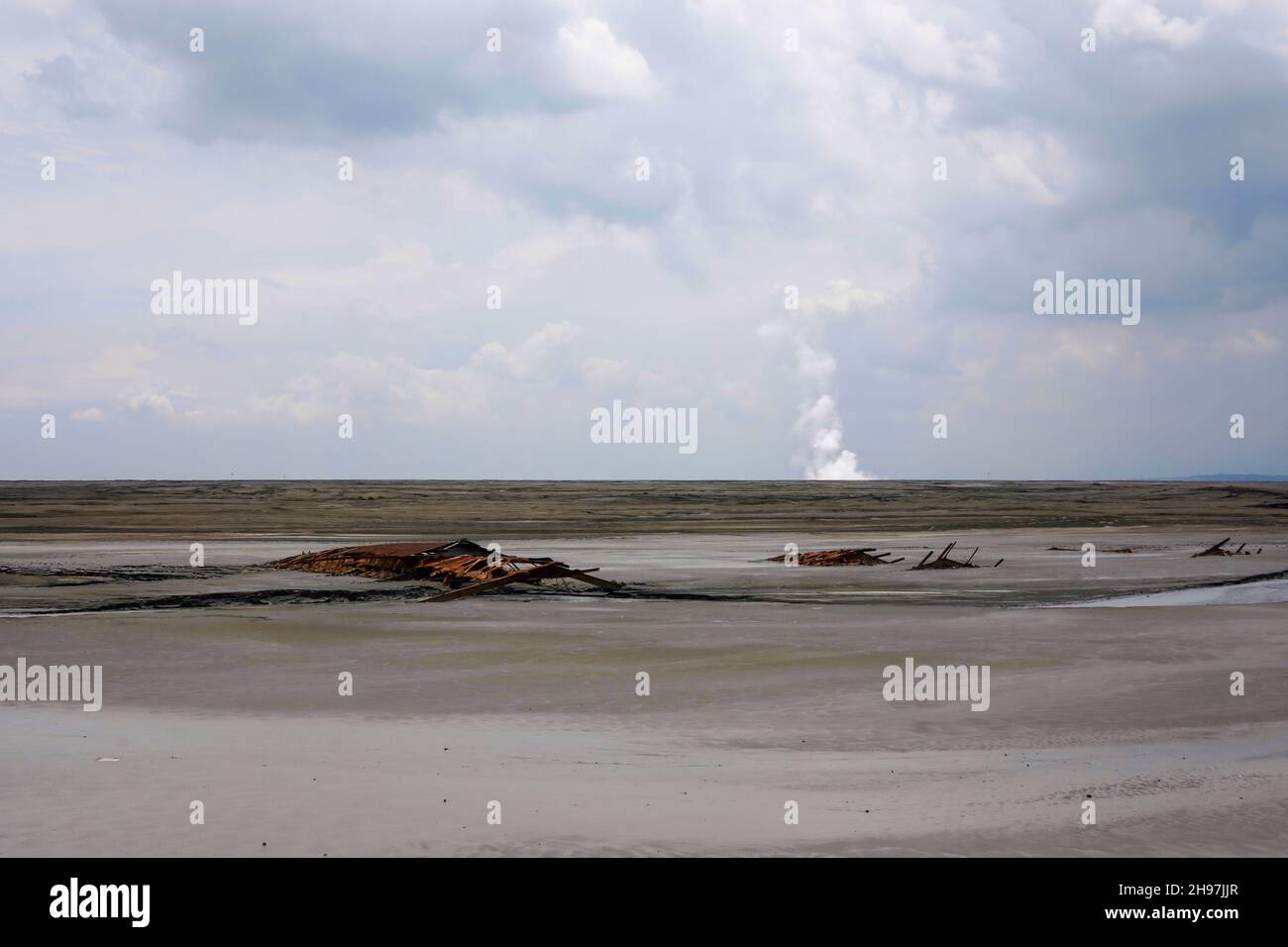 Lake of dry mud formed from a mud volcano eruption in Sidoarjo, Indonesia. Clouds in blue sky. Natural disaster in oil and gas industry. No people. Stock Photo