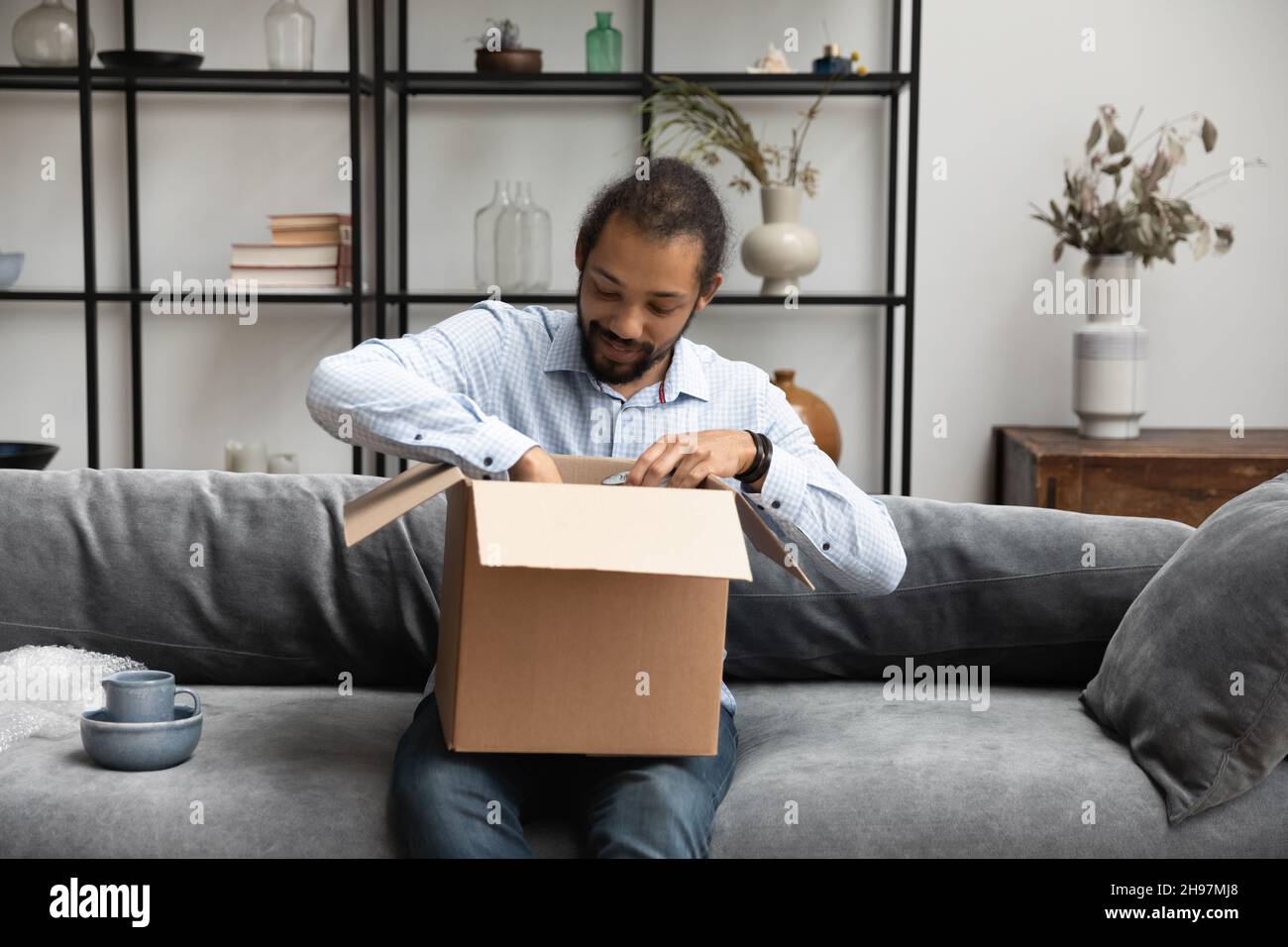 Happy young African American man unpacking cardboard box. Stock Photo