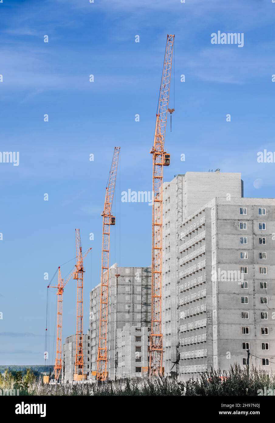 Building crane and building under construction against cloudy sky Stock Photo
