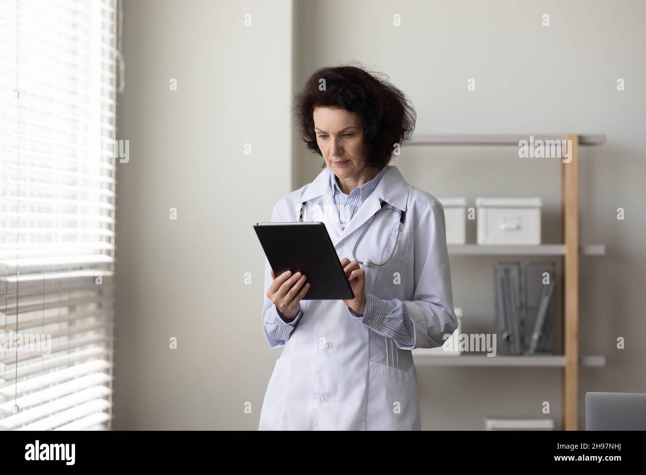 Serious mature female doctor using tablet computer Stock Photo