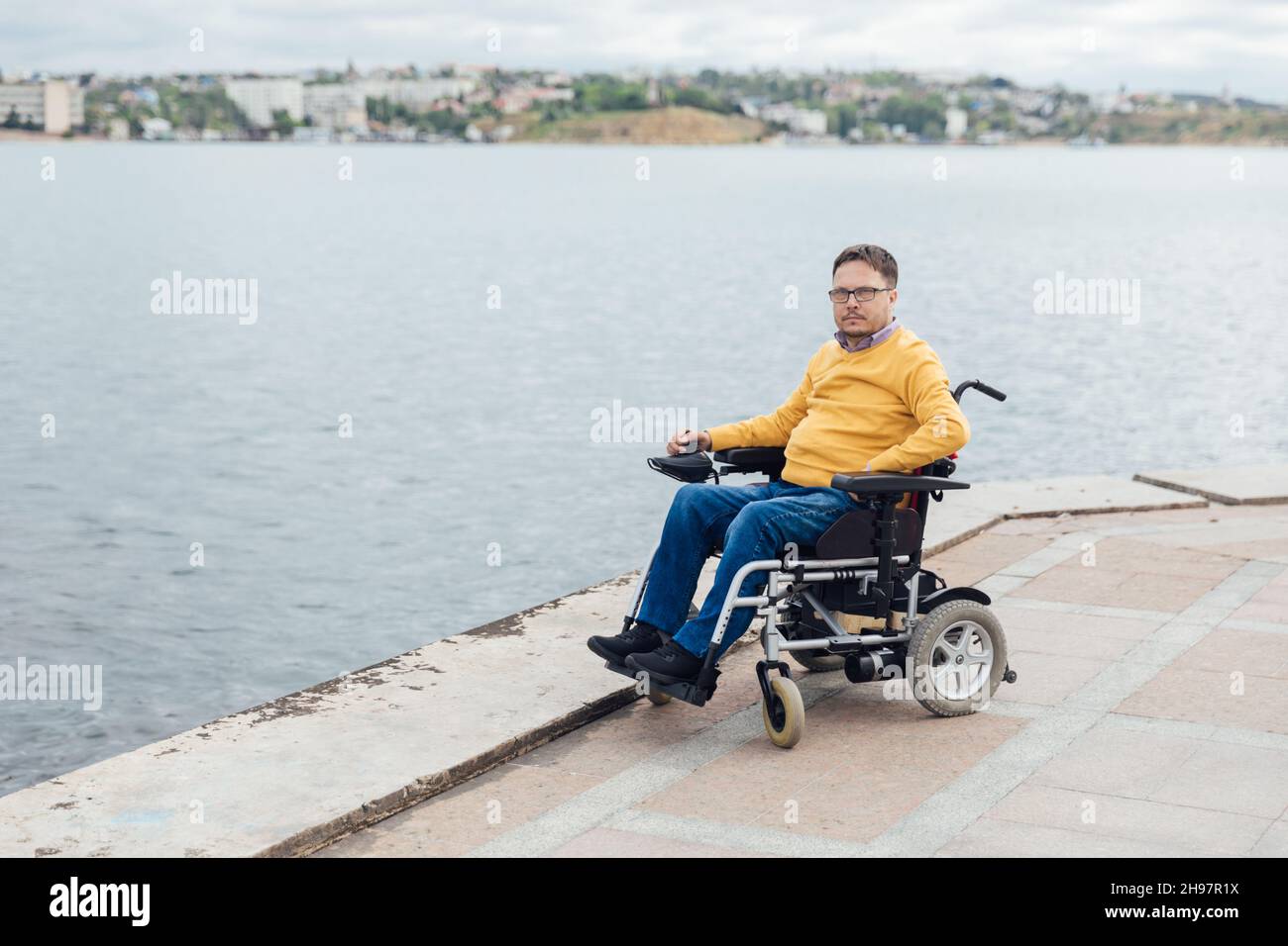 a man with disabilities in a wheelchair walks around the city Stock