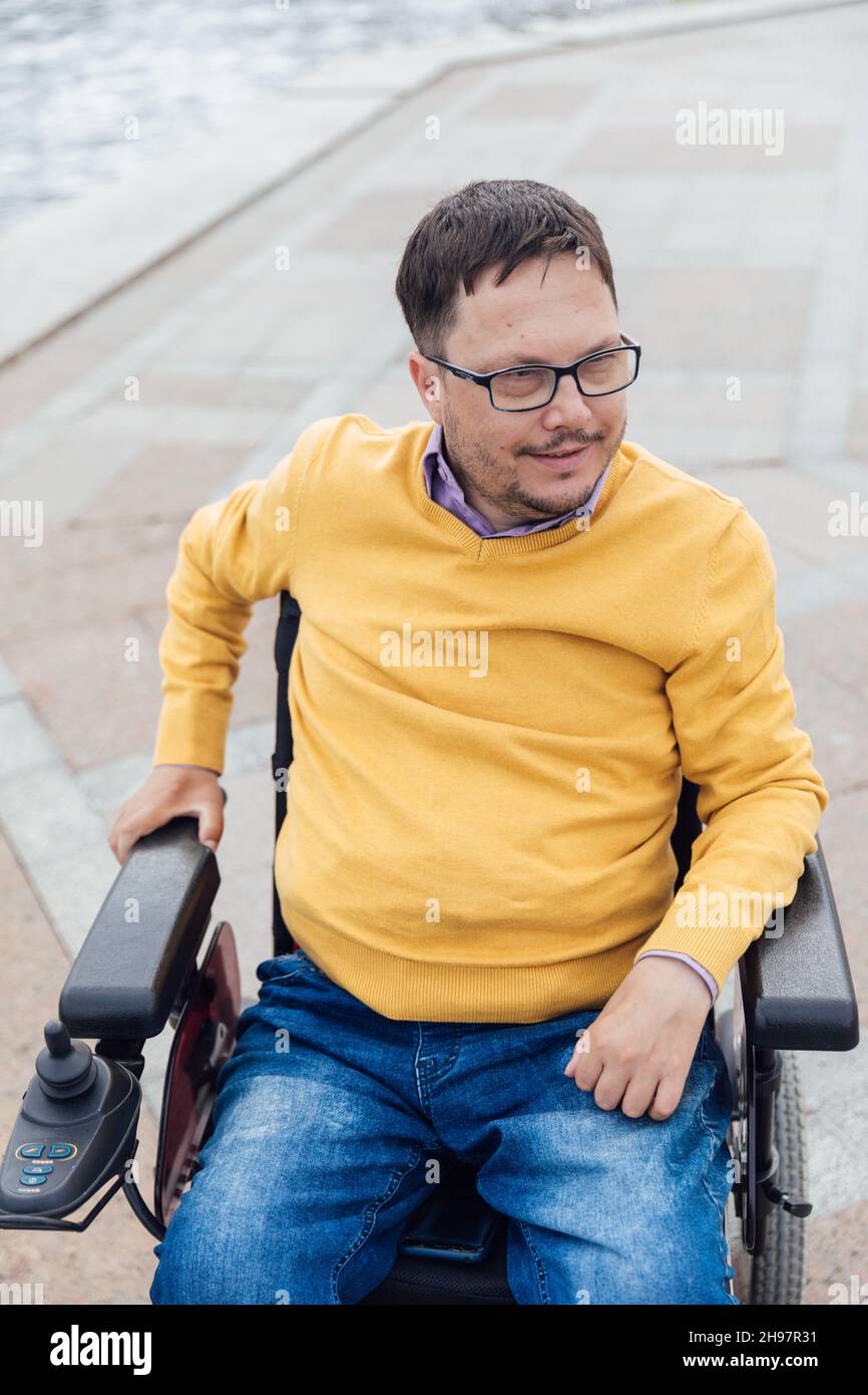a man with disabilities in a wheelchair walks around the city Stock