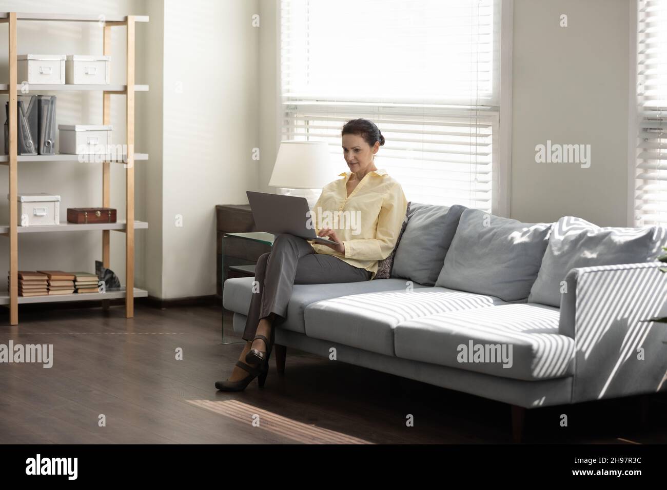 Middle aged business lady using laptop computer on couch Stock Photo