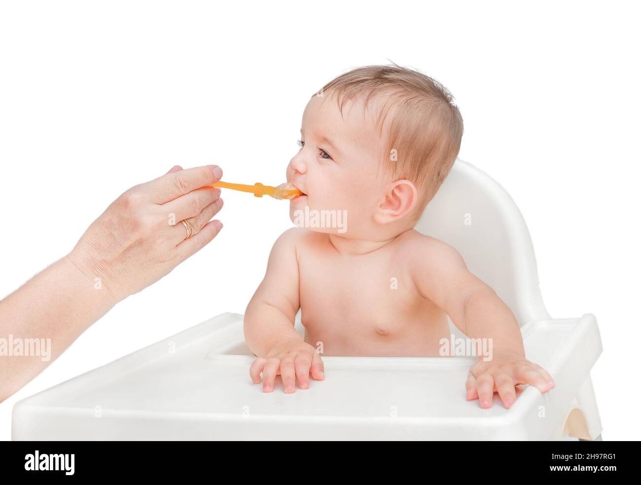 The first feeding of the baby. Hand holds out a spoon with mashed potatoes to a child Stock Photo