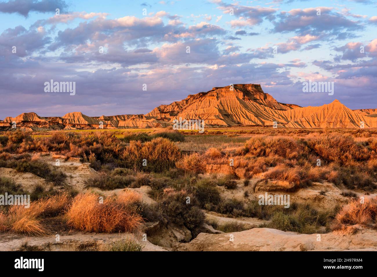 Red glowing mountain range against cloudy sky - Banderas Reales, Arguedas, Spain Stock Photo