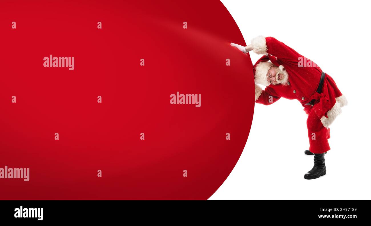 Santa Claus pushing huge bag of gifts isolated on white with copy space ...