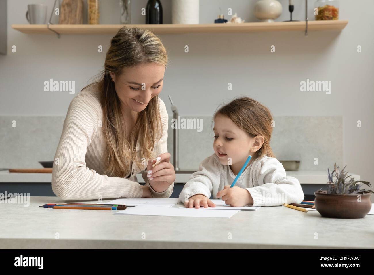 Caring young 35s woman teaching small girl writing letters Stock Photo ...