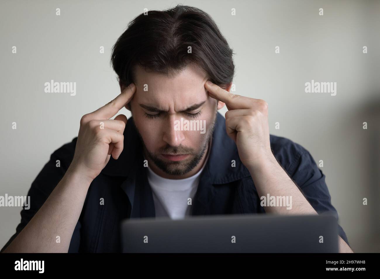 Concentrated serious young employee man holding head Stock Photo