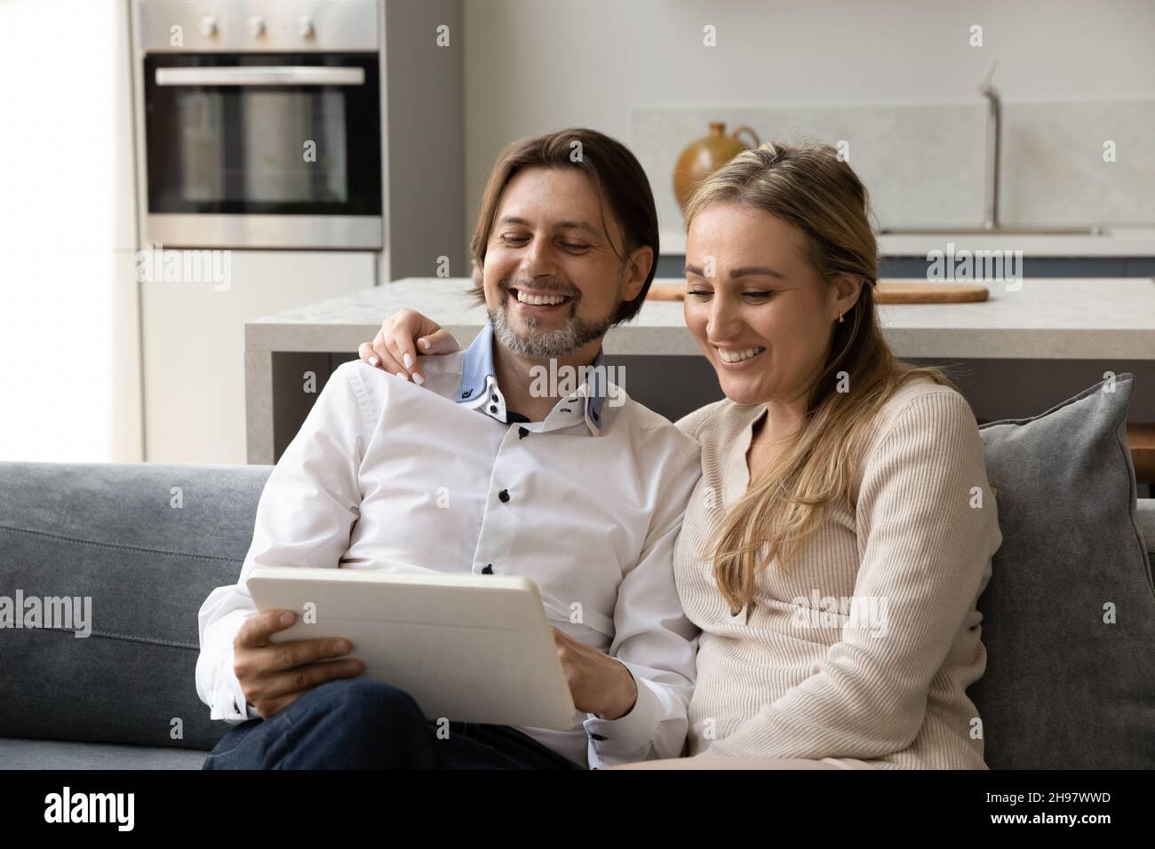 Happy bonding couple using digital tablet at home. Stock Photo