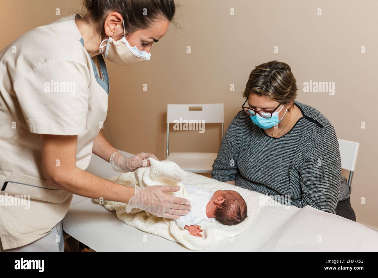 Professional physiotherapist doing an evaluation of the temporomandibular joints on a newborn baby. Stock Photo