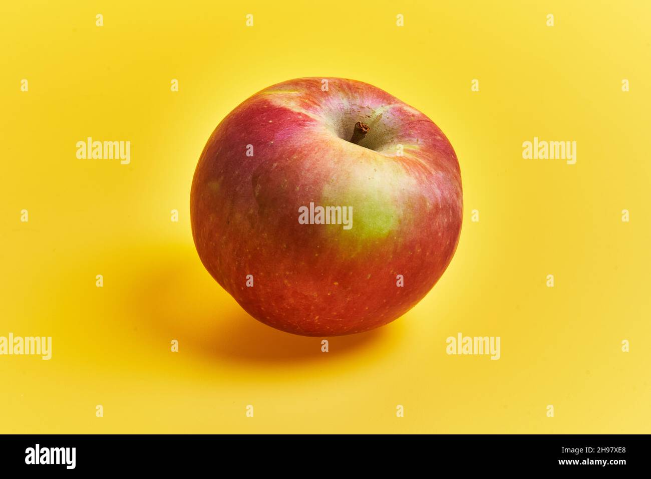 Single red apple fruit over yellow background Stock Photo - Alamy