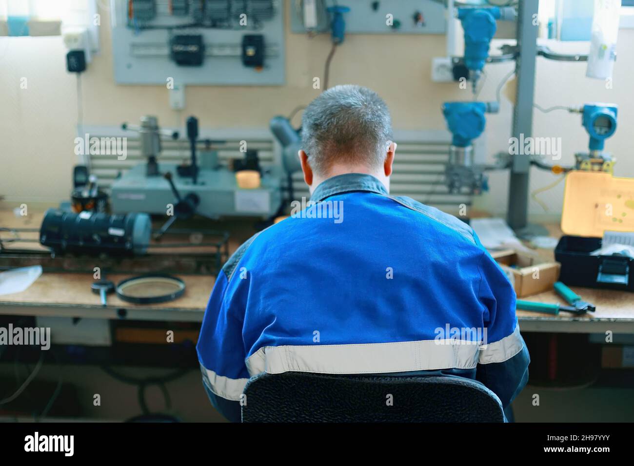 Training in working specialties. Young worker sits at desk with equipment in training center. Advanced training and training of technicians and locksmiths. Instrumentation and automation. Stock Photo