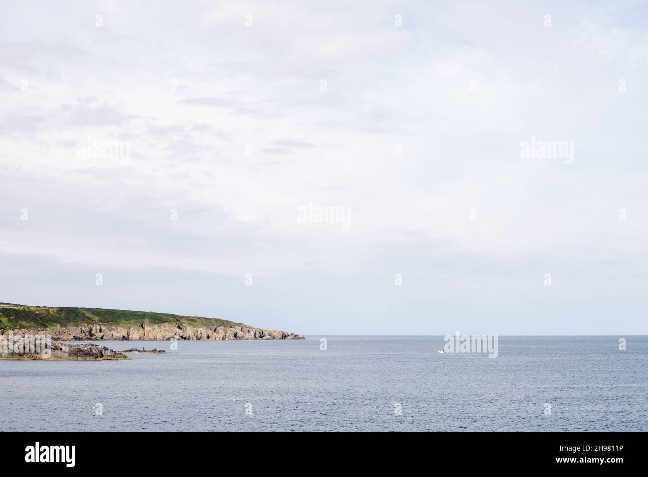View along the rugged coast looking west from the harbour of Portsoy with a small lobster boat out collecting creels. Stock Photo