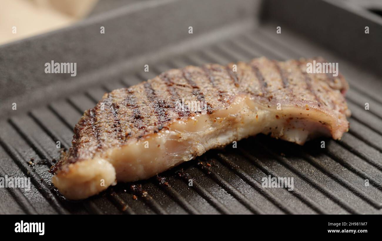 frying new york steak with tongs on grill pan, wide photo Stock Photo