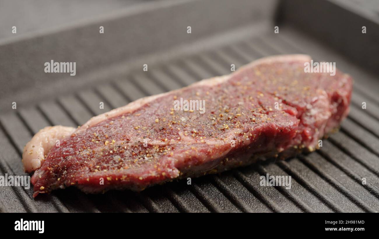 Premium Photo  Frying new york strip steak in cast iron frying pan over  the electric stove