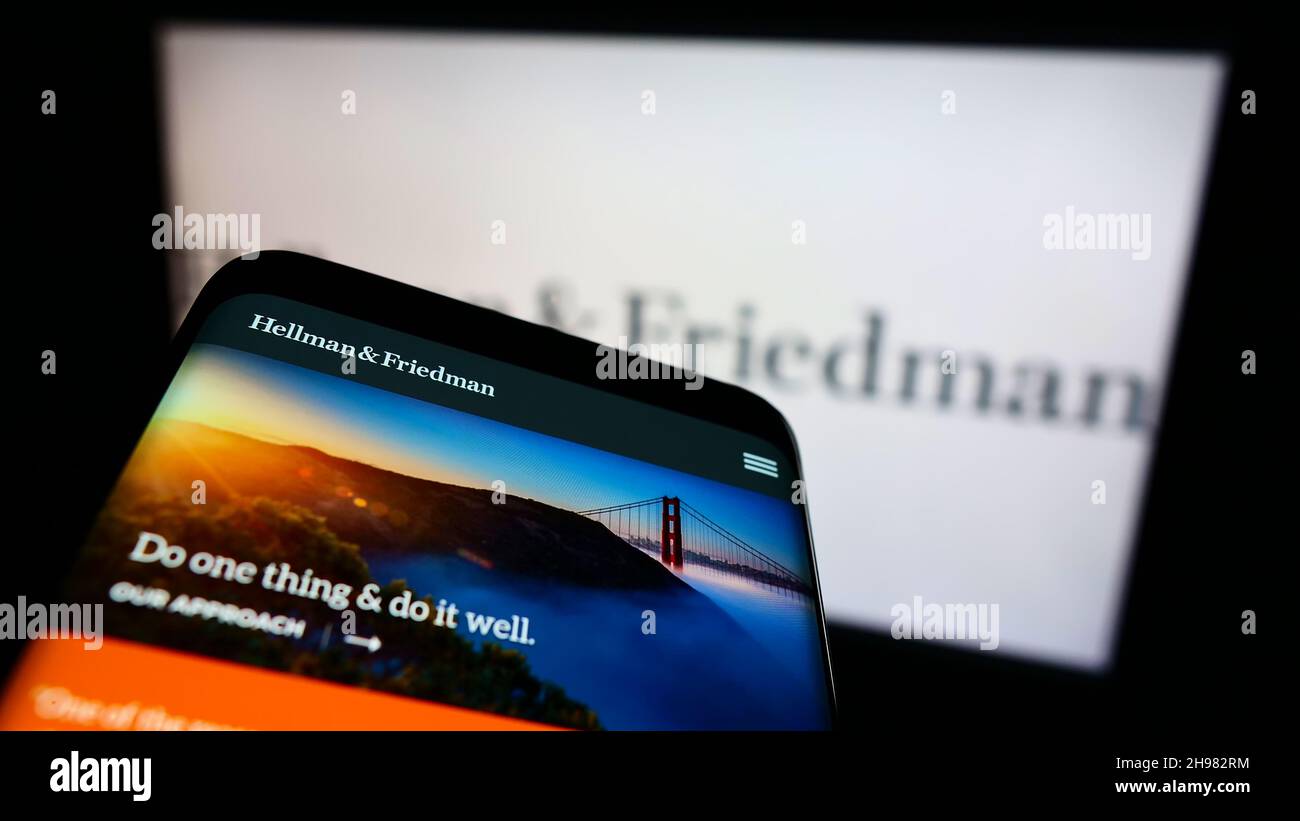 Mobile phone with website of American private equity company Hellman and Friedman LLC on screen in front of logo. Focus on top-left of phone display. Stock Photo