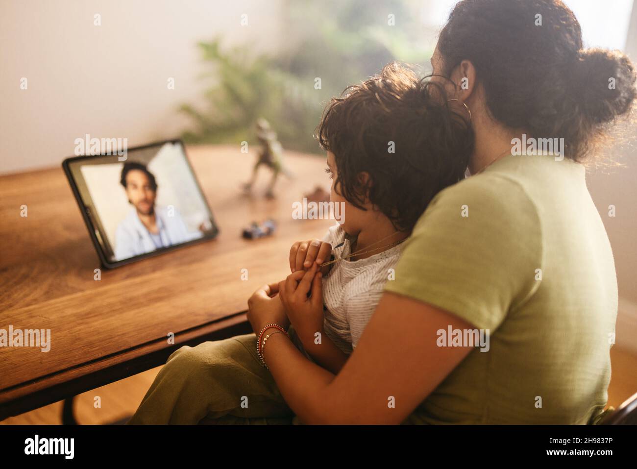 Mother and child video calling their family doctor on a digital tablet. Mother and son having an online consultation with their paediatrician. Loving Stock Photo