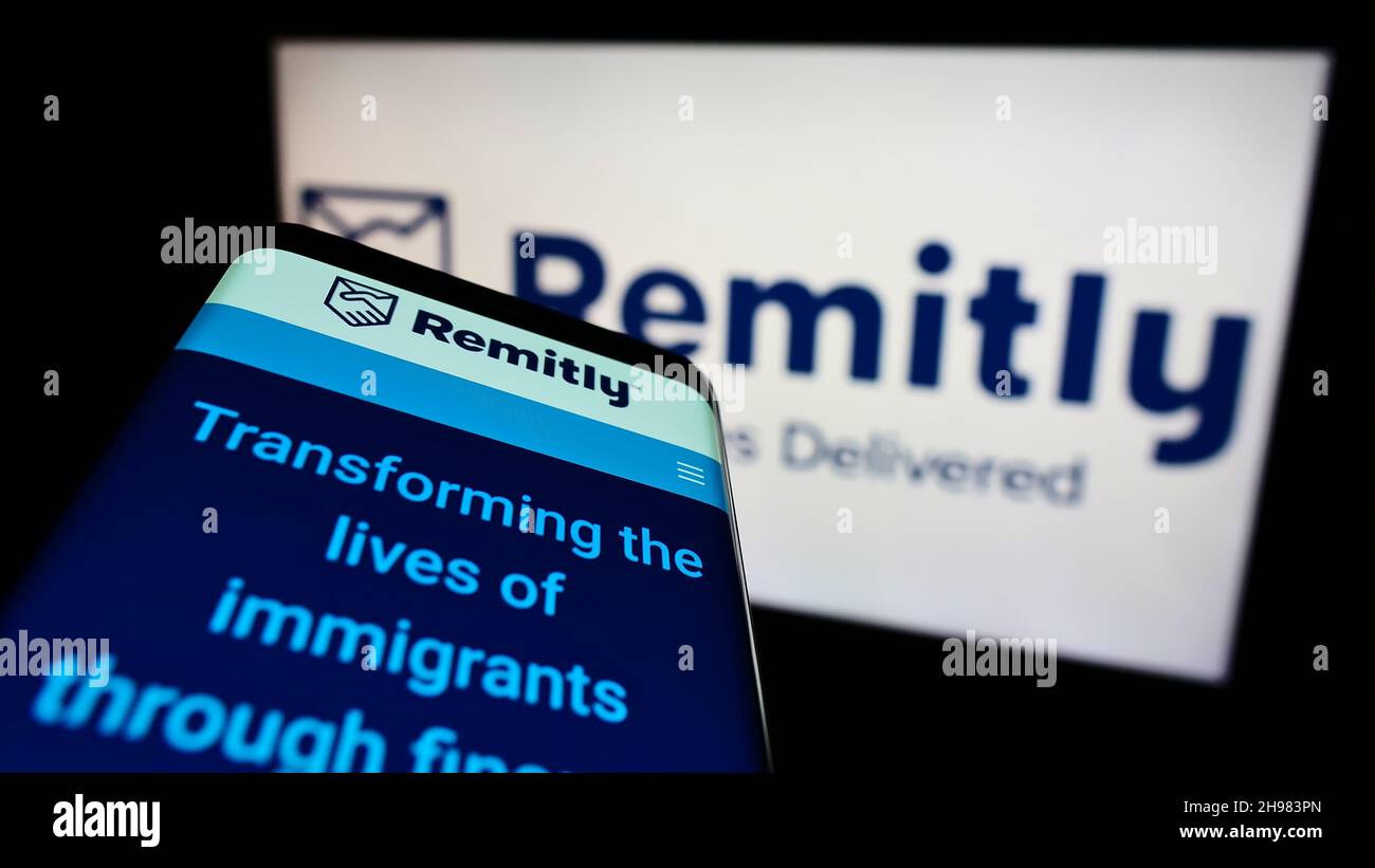 Cellphone with web page of US payment company Remitly Inc. on screen in front of business logo. Focus on top-left of phone display. Stock Photo