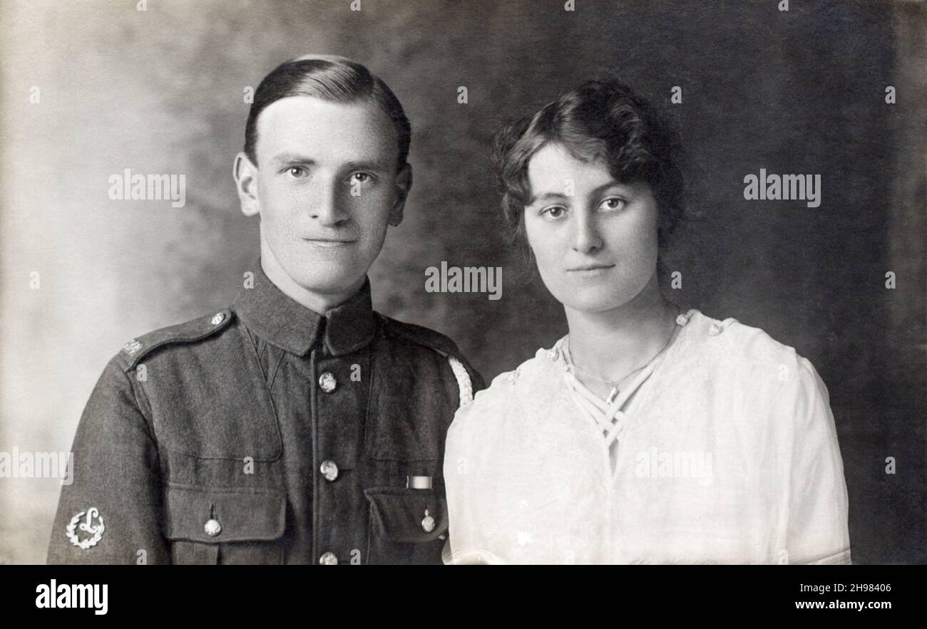 A portrait a First World War British soldier, a Gunner in the Royal Field Artillary  (RFA), with a woman, possibly hid wife. The solider has the medal ribbon of the 1914 Star, also known as the 'Mons Star'. The letter 'L' in a wreath signies he is gun layer.  c,1917-1918. Stock Photo