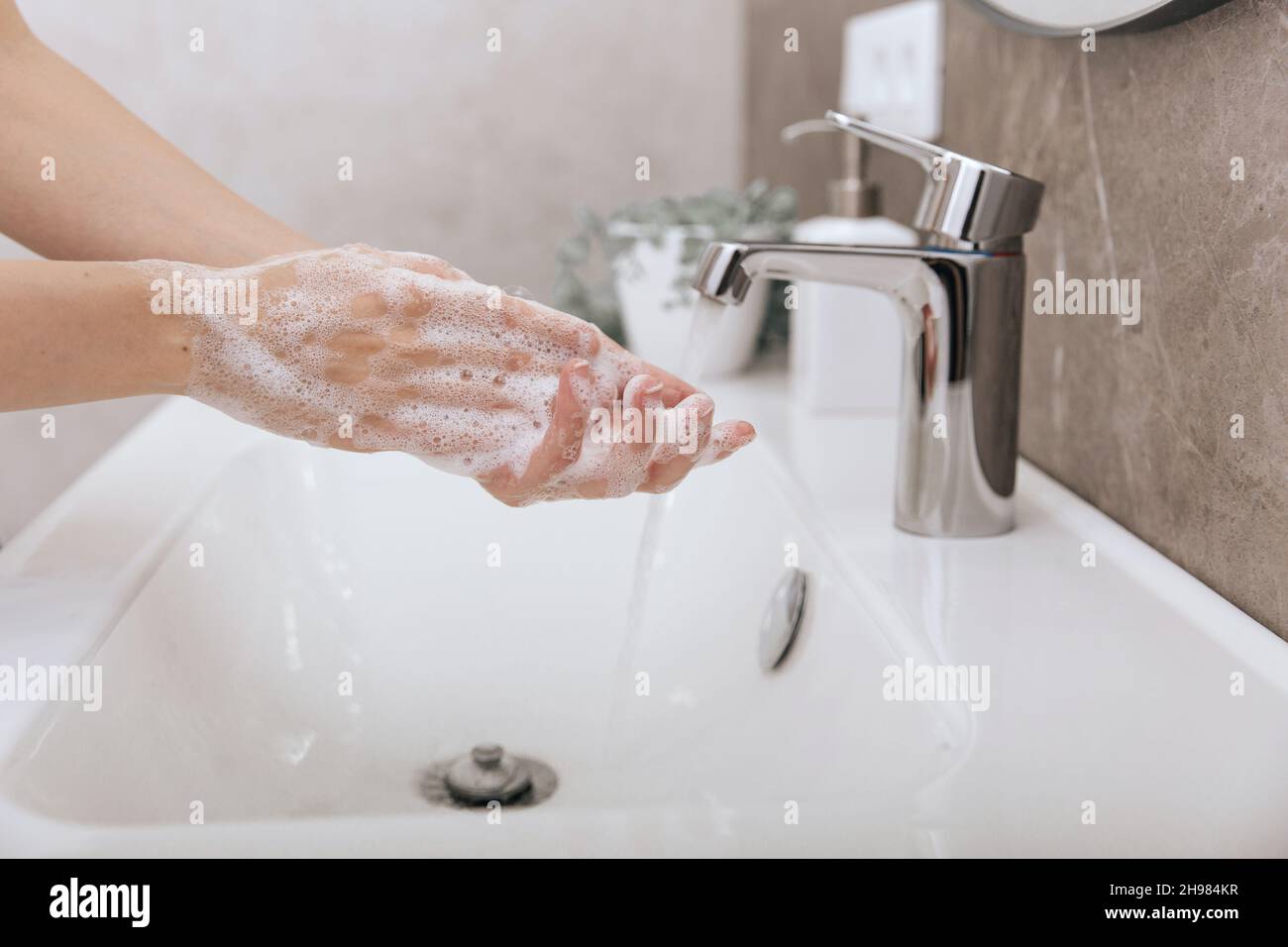 Washing hands under the flowing water tap. Hygiene concept hand detail. Washing hands rubbing with soap for corona virus prevention, hygiene to stop Stock Photo