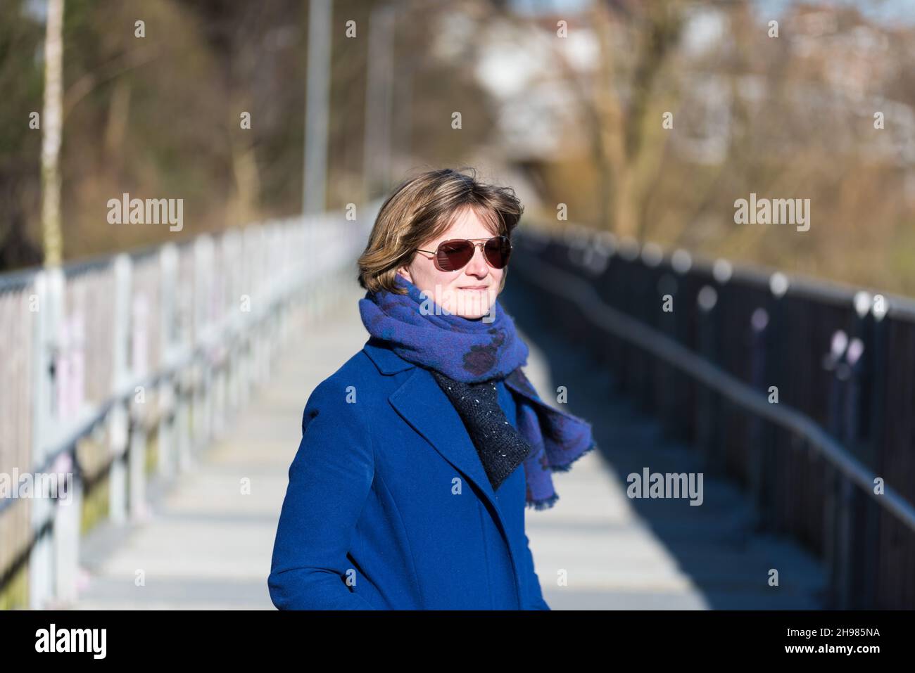 Outdoor portrait of a woman with a blue coat, a scarf and eyeglasses ...
