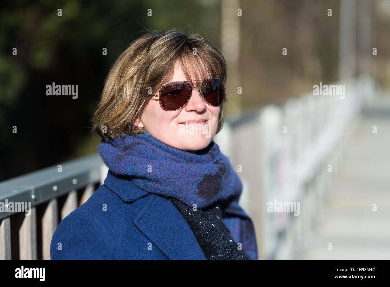 Outdoor portrait of a woman with a blue coat, a scarf and eyeglasses ...
