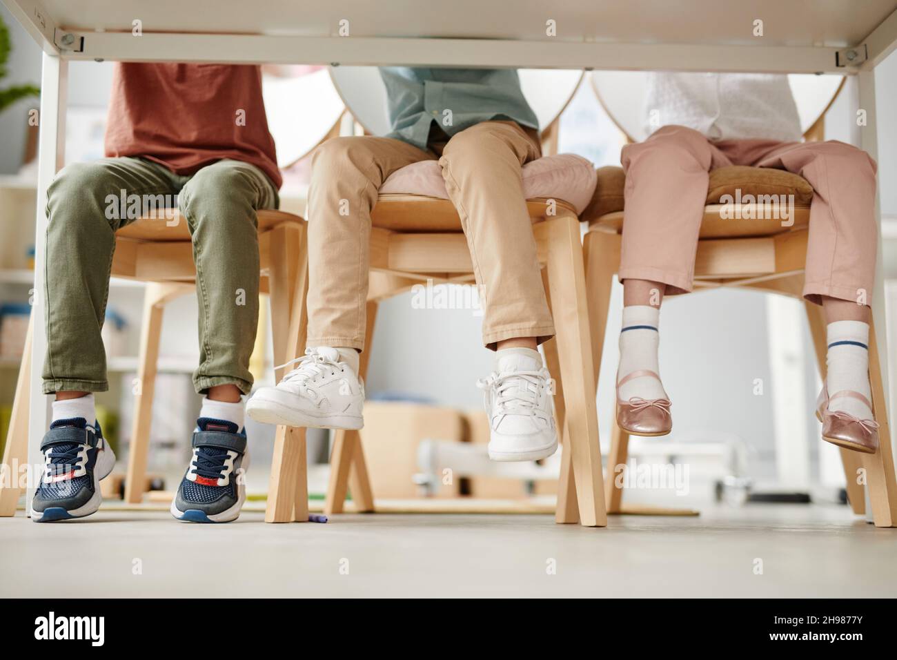Group of school children sitting on chairs at desk during a lesson in the classroom Stock Photo