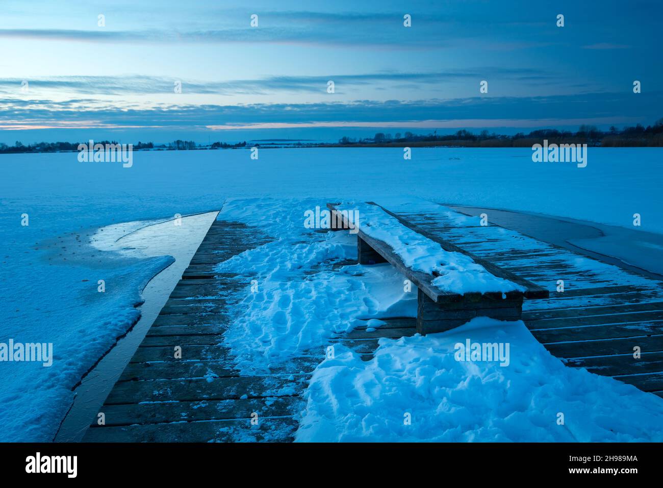 Snow on the pier with a bench and a frozen lake Stock Photo Alamy