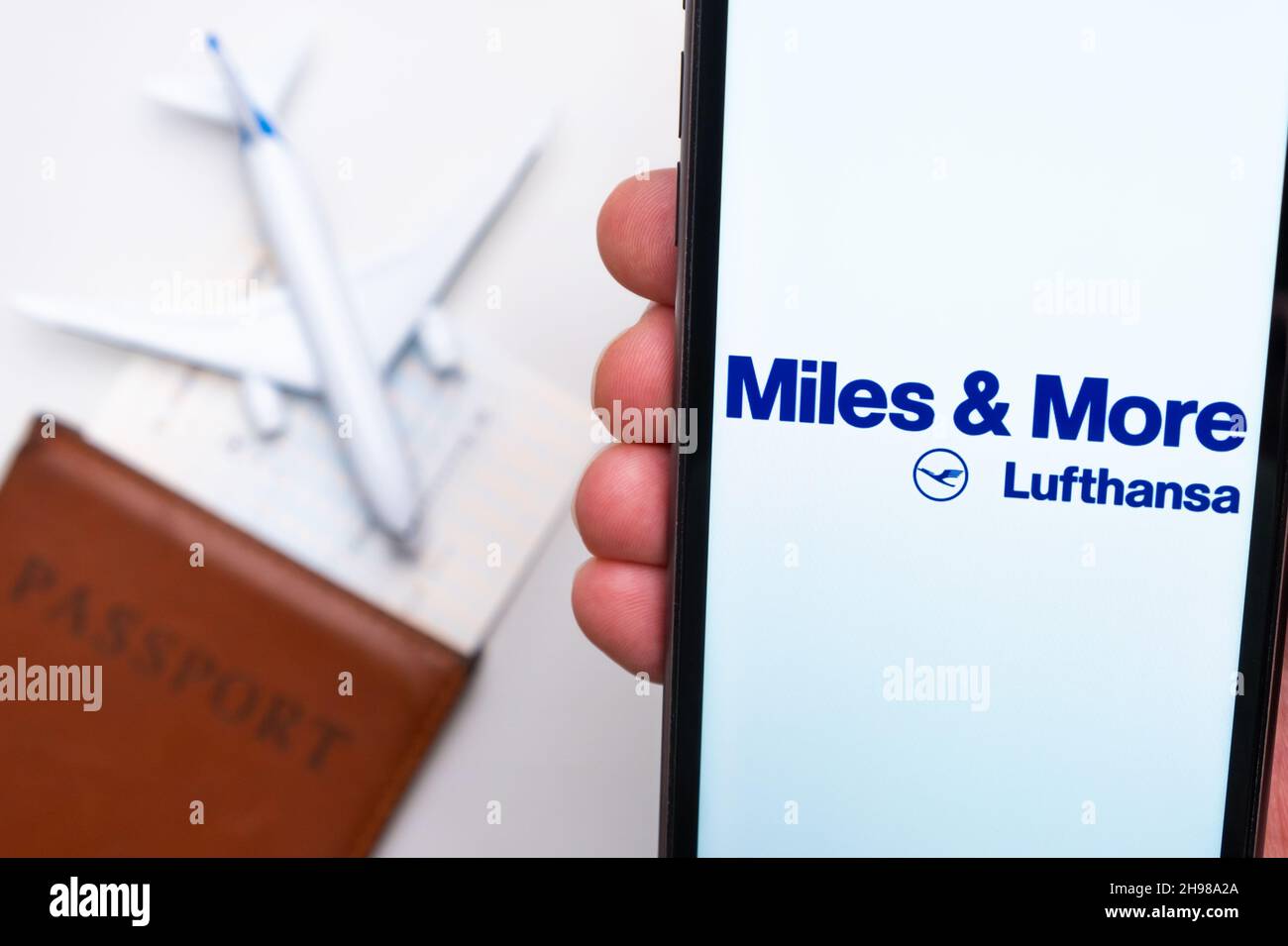 Miles More Lufthansa Airline logo on the mobile phone screen with a plane, passport and boarding pass on the background. The concept of the airlines mobile application. November 2021, San Francisco, USA Stock Photo