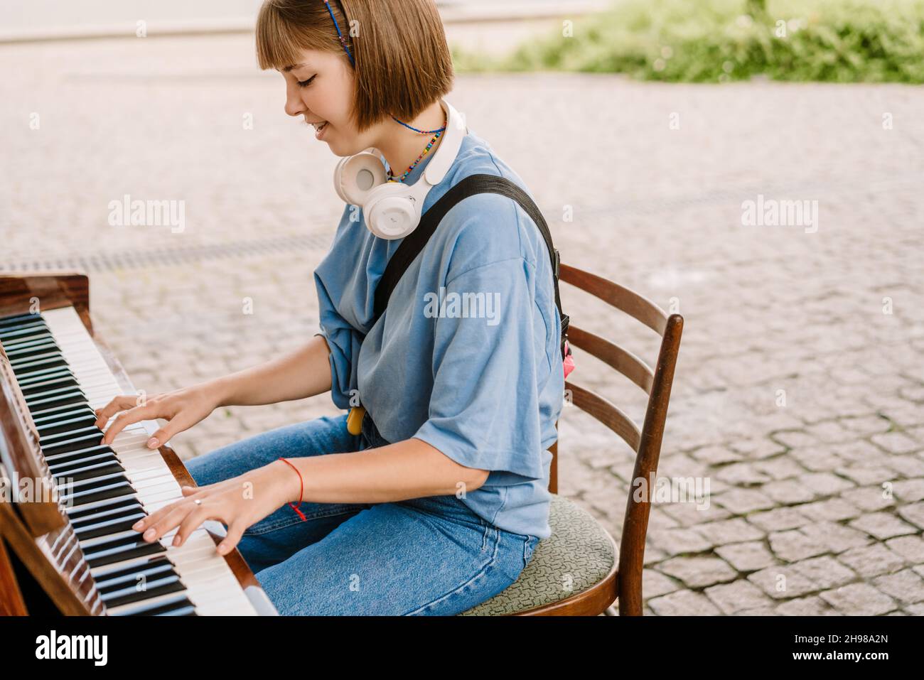 Young blonde woman with headphones playing piano in green park Stock Photo  - Alamy