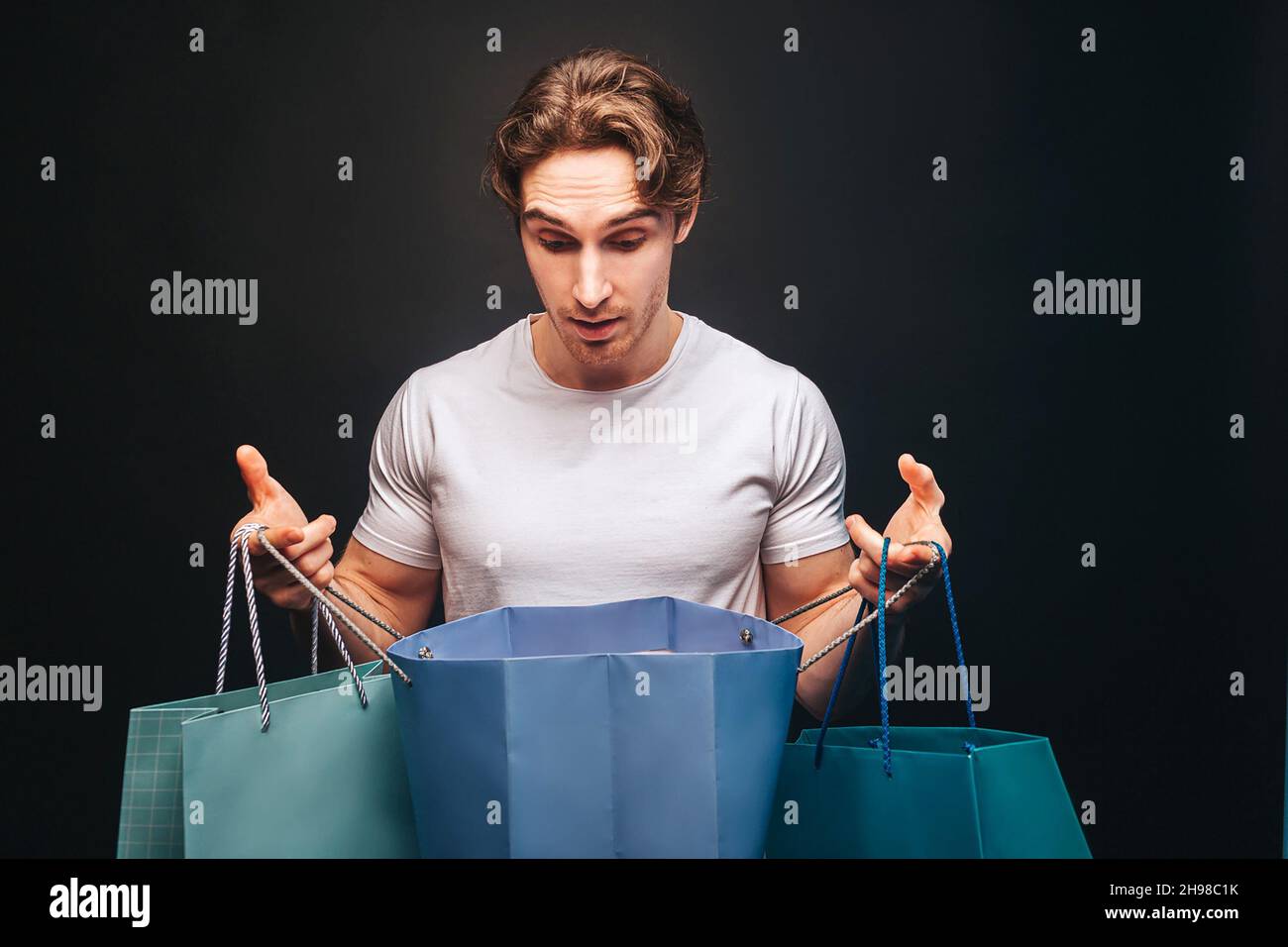 Surprised man looking in opened shopping bag Stock Photo