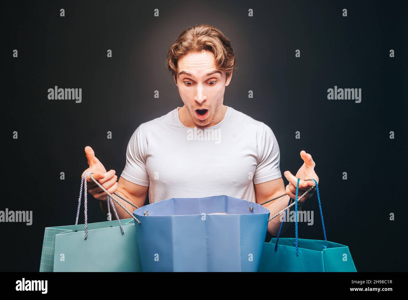 Shocked man looking in opened shopping bag Stock Photo