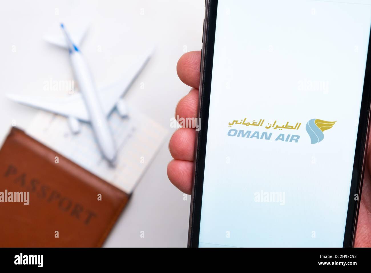Oman Air Airline logo on the mobile phone screen with a plane, passport and boarding pass on the
