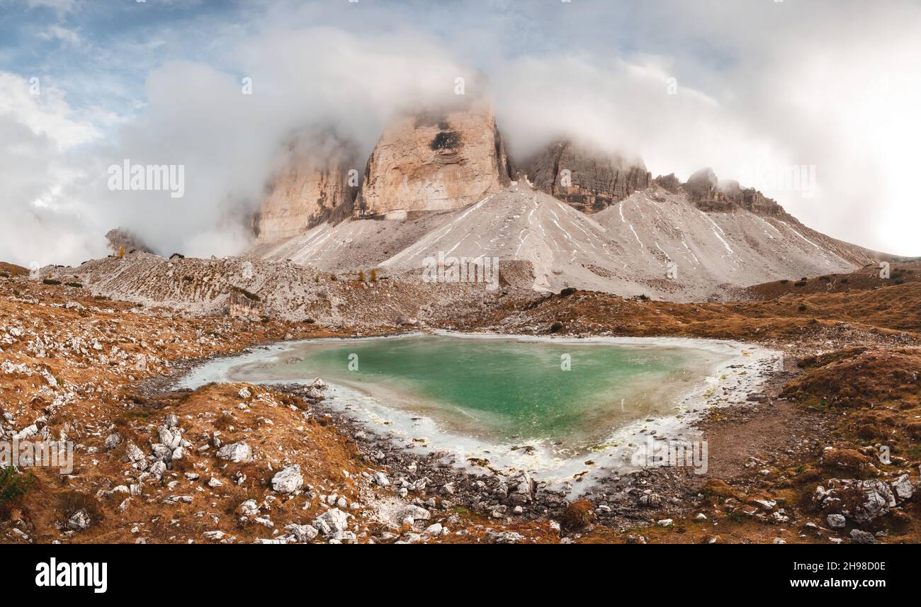 Clear turquoise water of alpine lake Rienzquelle in the Tre Cime Di Laveredo National Park, Dolomites, Italy. Picturesque landscape with snowy mountains, and small frozen lake in autumn Dolomite Alps Stock Photo