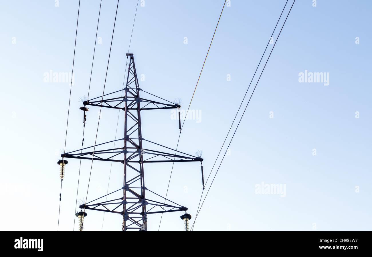 High voltage power lines, post or tower against the backdrop of a beautiful sky. Sequentially ordered high energy pylons. Stock Photo