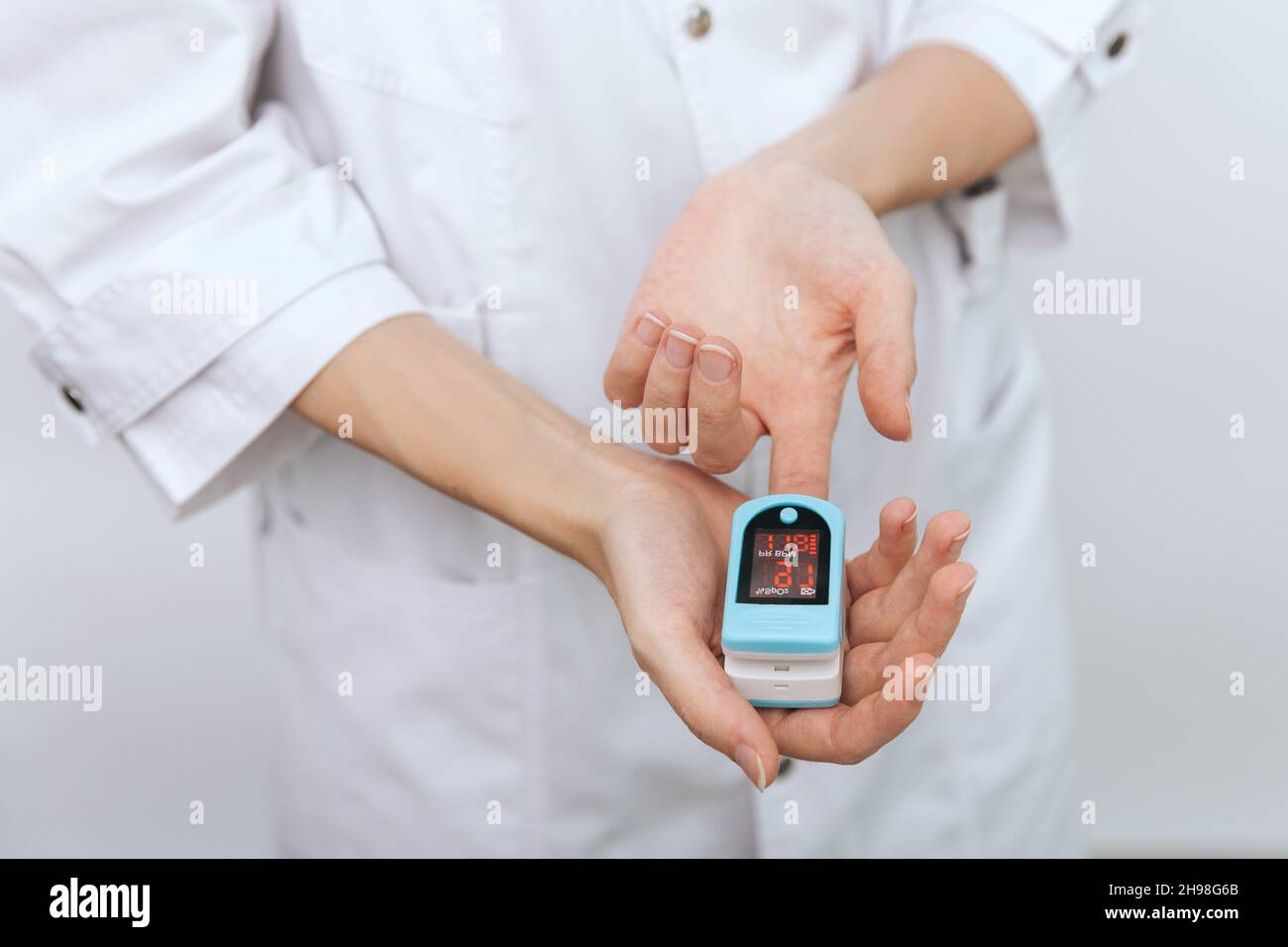 Pulse oximeter with hand of doctor isolated on white. The concept of portable digital device to measure person's oxygen saturation. Measuring oxygen Stock Photo