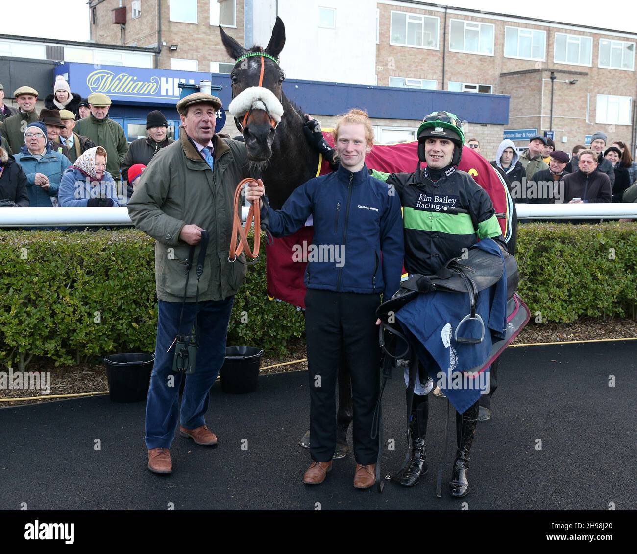 Connections of First Flow ridden by David Bass (right) and trainer Kim Bailey (left) after winning The Fitzdares Peterborough Steeple Chase at Huntingdon racecourse. Picture date: Sunday December 5, 2021. Stock Photo