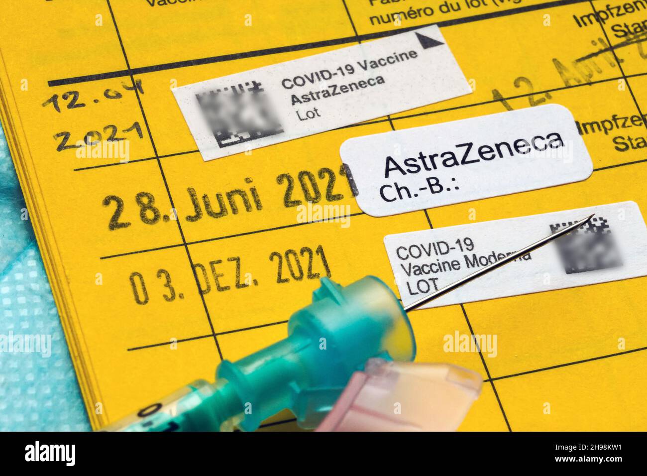 Syringe on a german vaccination card with the note of three vaccinations against Covid-19, booster vaccination - December 5, 2021   ---   Spritze auf einem Impfausweis mit dem Eintrag von drei Impfungen gegen Covid-19, Booster-Impfung - 5.12.2021 Stock Photo