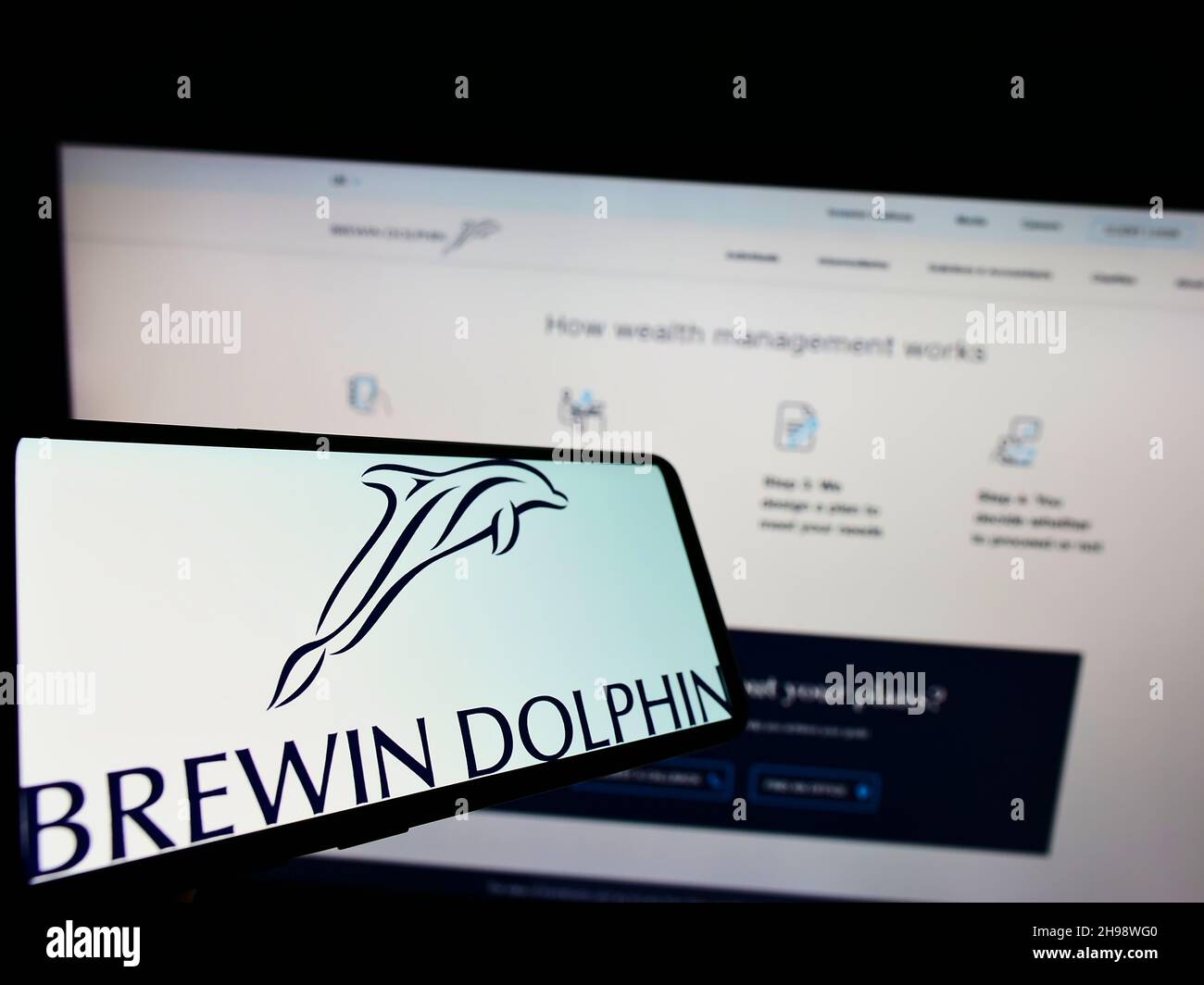 Smartphone with logo of British wealth management company Brewin Dolphin plc on screen in front of website. Focus on center of phone display. Stock Photo