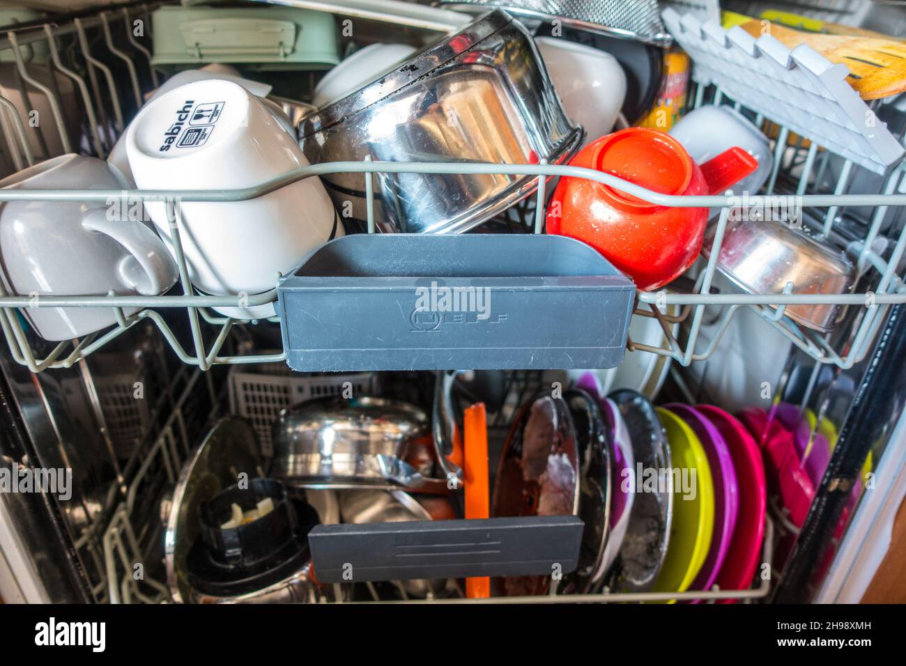 A fully loaded dishwasher with mixed plastic and earthenware Stock