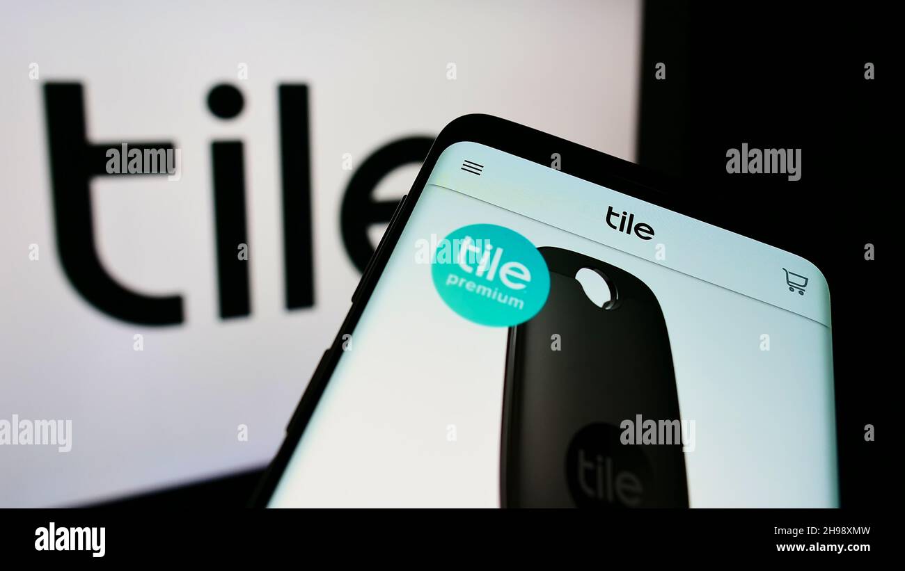 Mobile phone with webpage of US consumer electronics company Tile Inc. on screen in front of business logo. Focus on top-left of phone display. Stock Photo