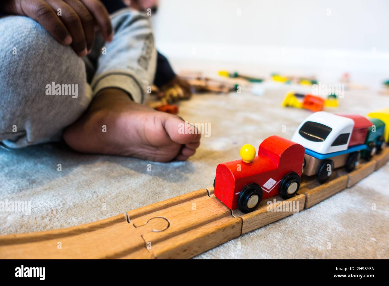 Boy playing with train toy. Indian boy aged 3 playing with a wooden train track and trains set Stock Photo