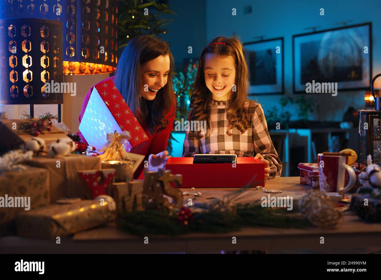 Cute daughter unboxing with mom the Christmas present - electronic device Stock Photo