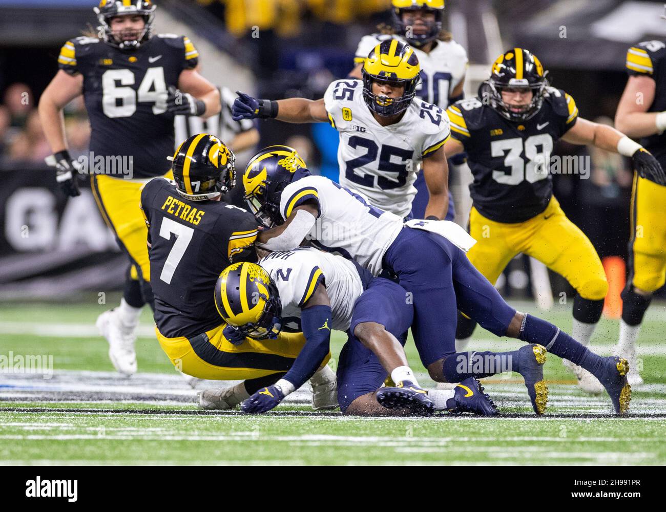 Indianapolis, Indiana, USA. 04th Dec, 2021. Michigan linebacker Josh Ross (12) and Michigan defensive back Brad Hawkins (2) make the tackle on Iowa quarterback Spencer Petras (7) during NCAA Football game action between the Michigan Wolverines and the Iowa Hawkeyes at Lucas Oil Stadium in Indianapolis, Indiana. Michigan defeated Iowa 42-3. John Mersits/CSM/Alamy Live News Stock Photo
