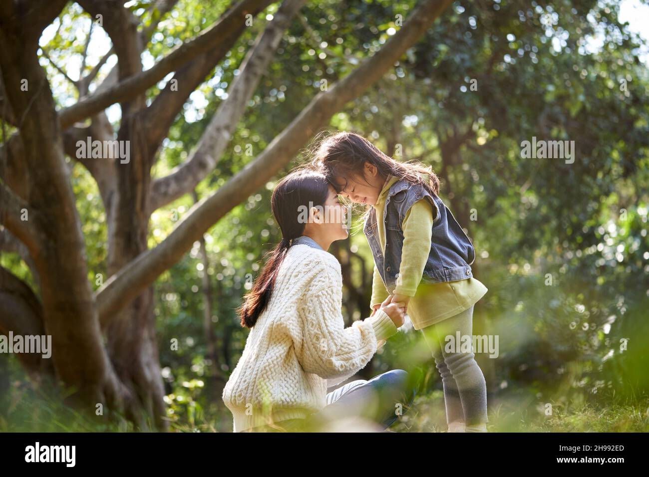 young asian mother and daughter enjoying a good time outdoors in city park Stock Photo