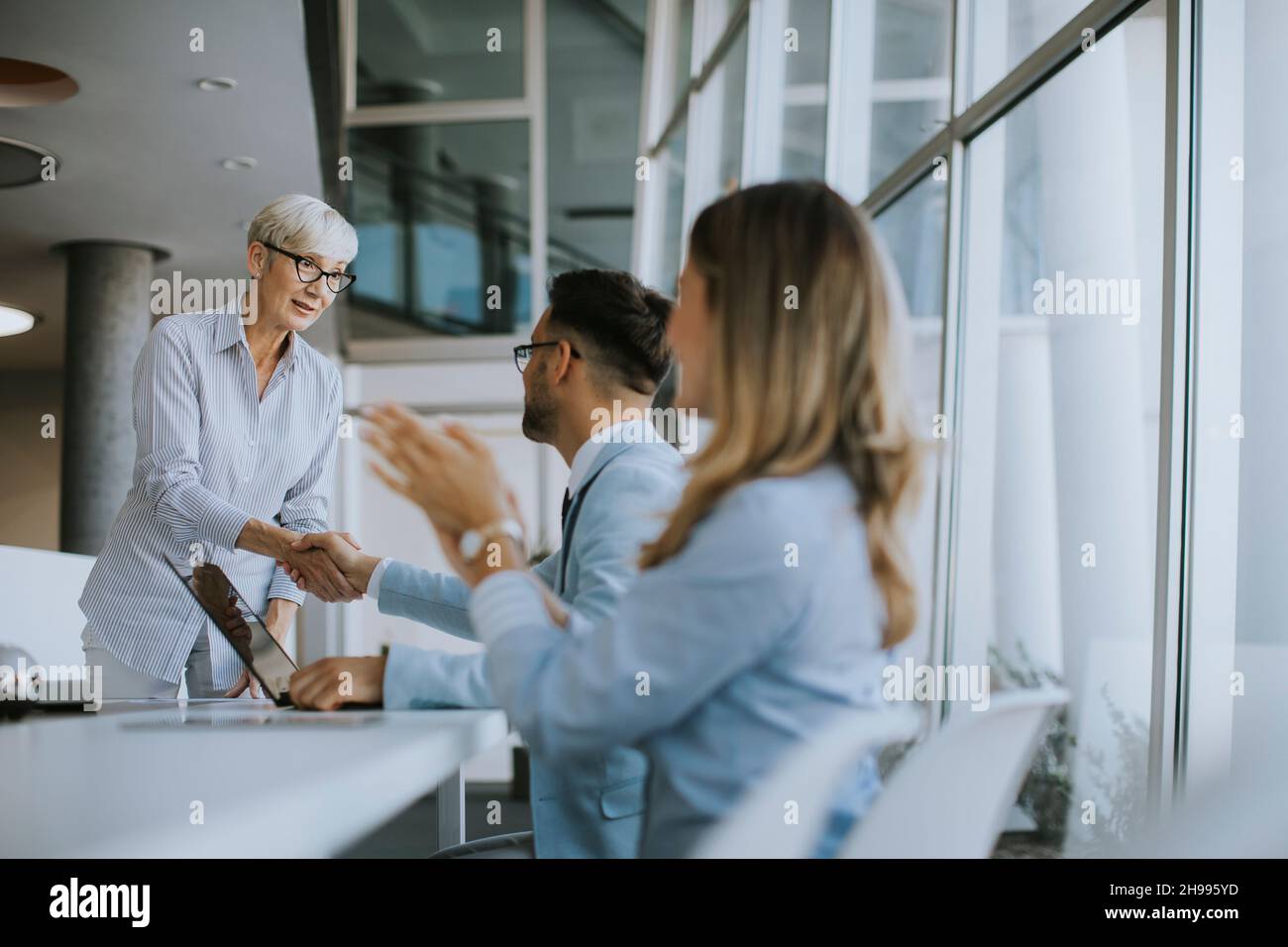 Mature business woman handshaking with young colleague on a meeting in the office Stock Photo