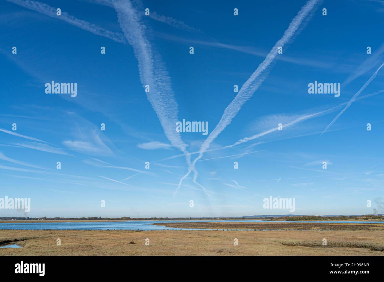 Looking into Pagham Harbour and towards the South Downs with blue skies and con trails. Stock Photo